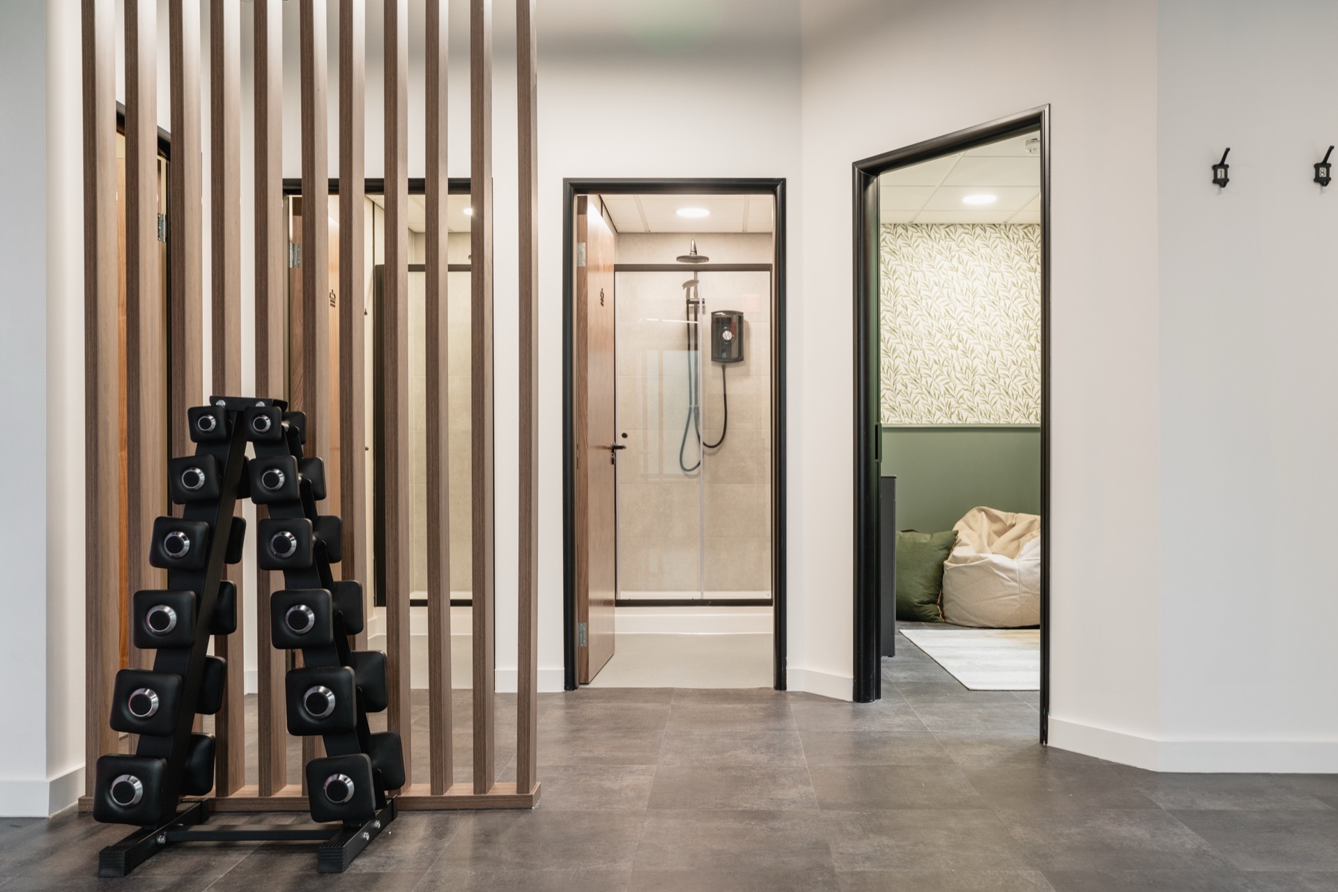 Shower room at Bagnalls, with a walk-in shower and changing space behind a timber slat screen, and a weights rack alongside