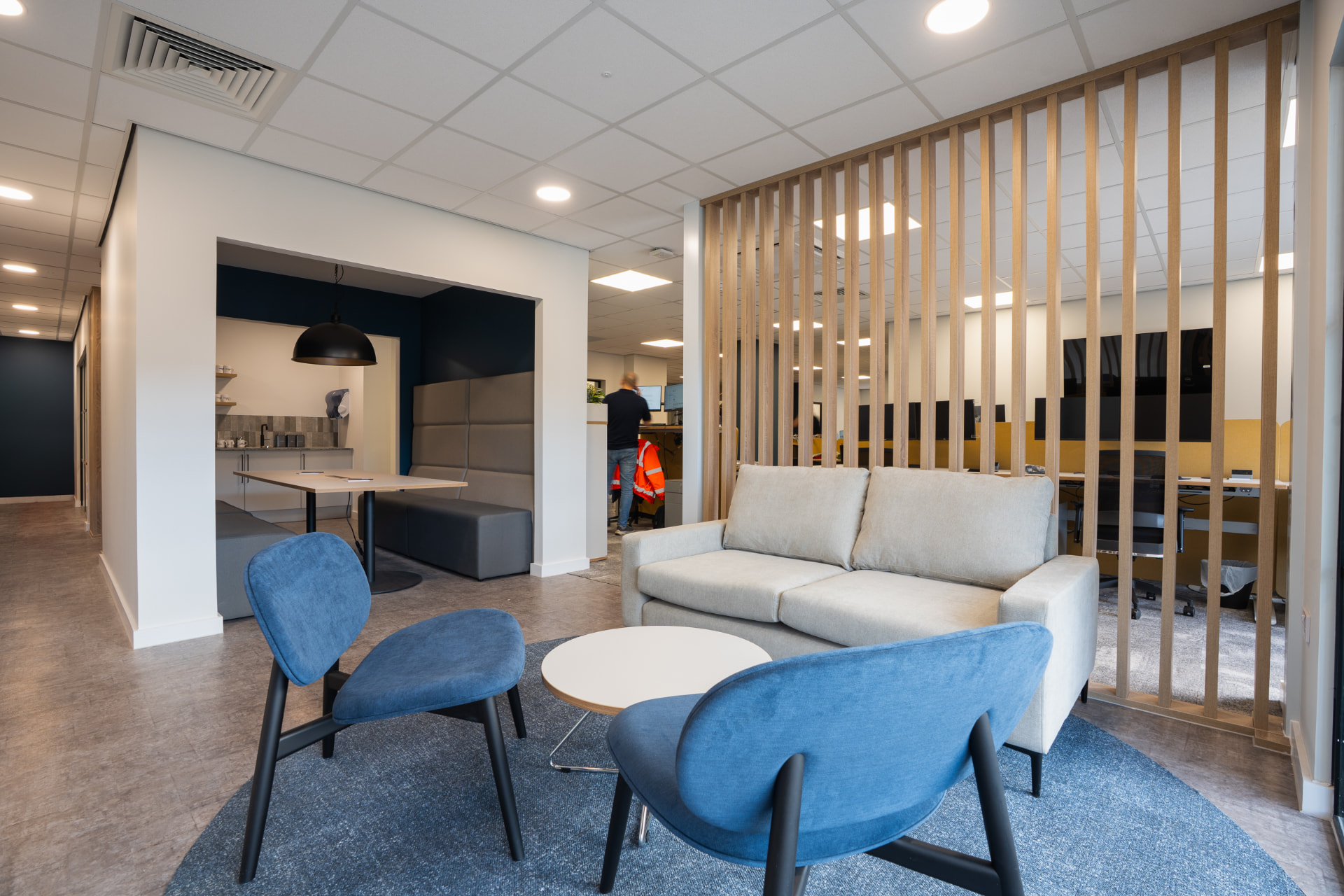 Refurbished office lounge with soft seating, warm timber and pendant lighting