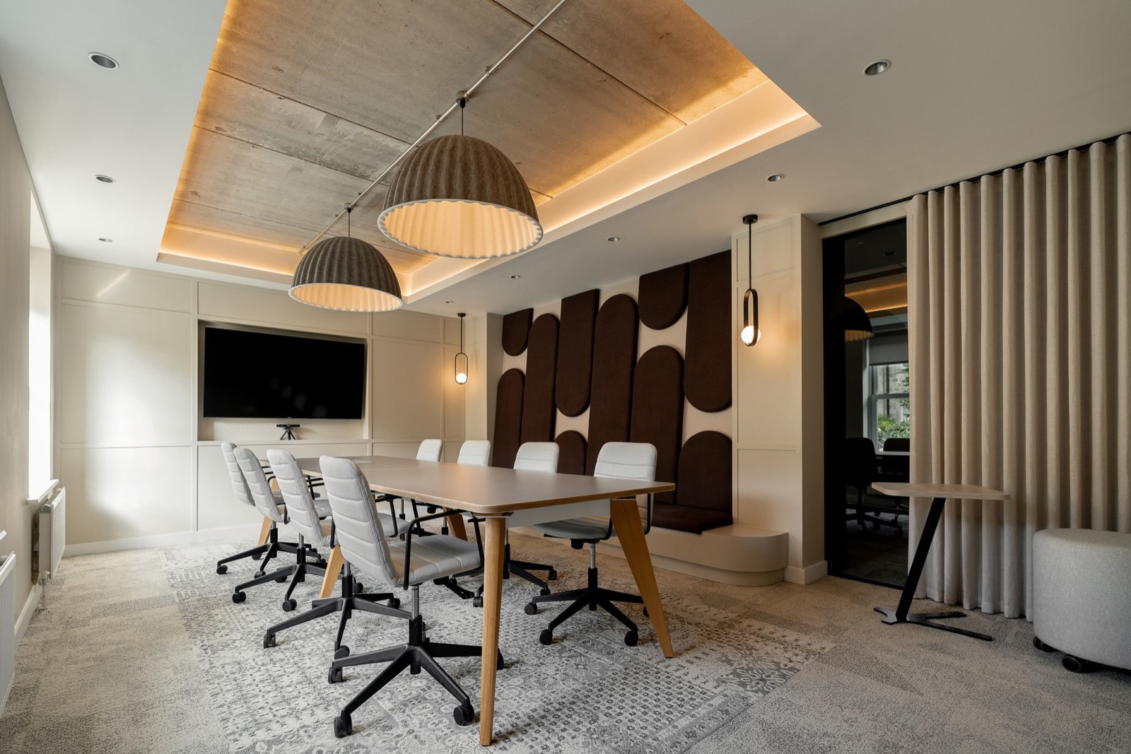 Meeting room at the Building Interiors studio, with a timber ceiling raft, fluted dome pendants and a sculpted brown felt acoustic wall