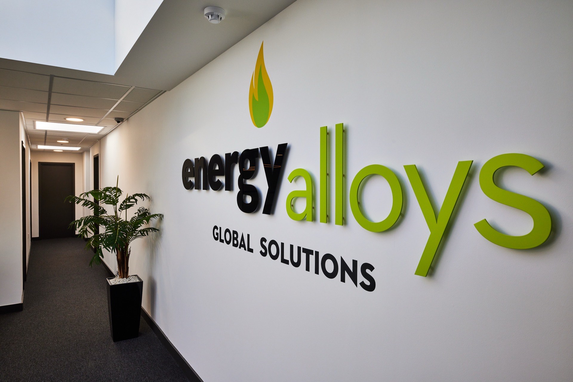 Reception corridor at Energy Alloys, with illuminated company signage and planting