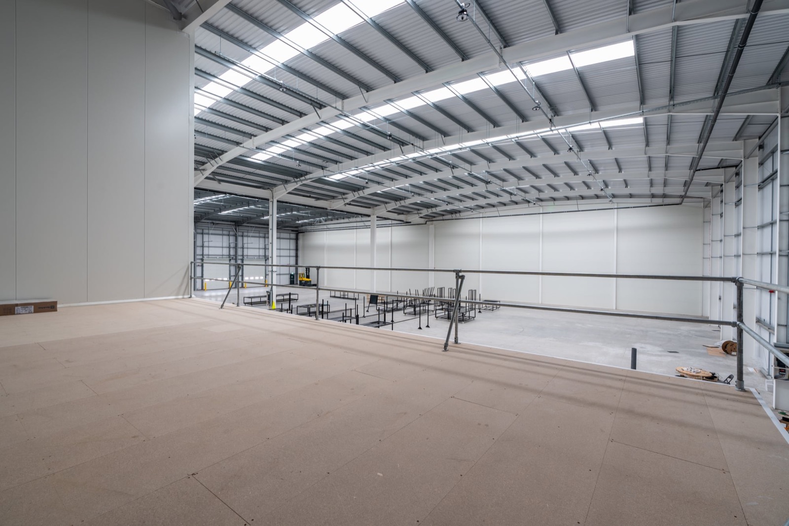 Empty mezzanine floor shell at Garolla, mid-construction, with exposed steel roof trusses