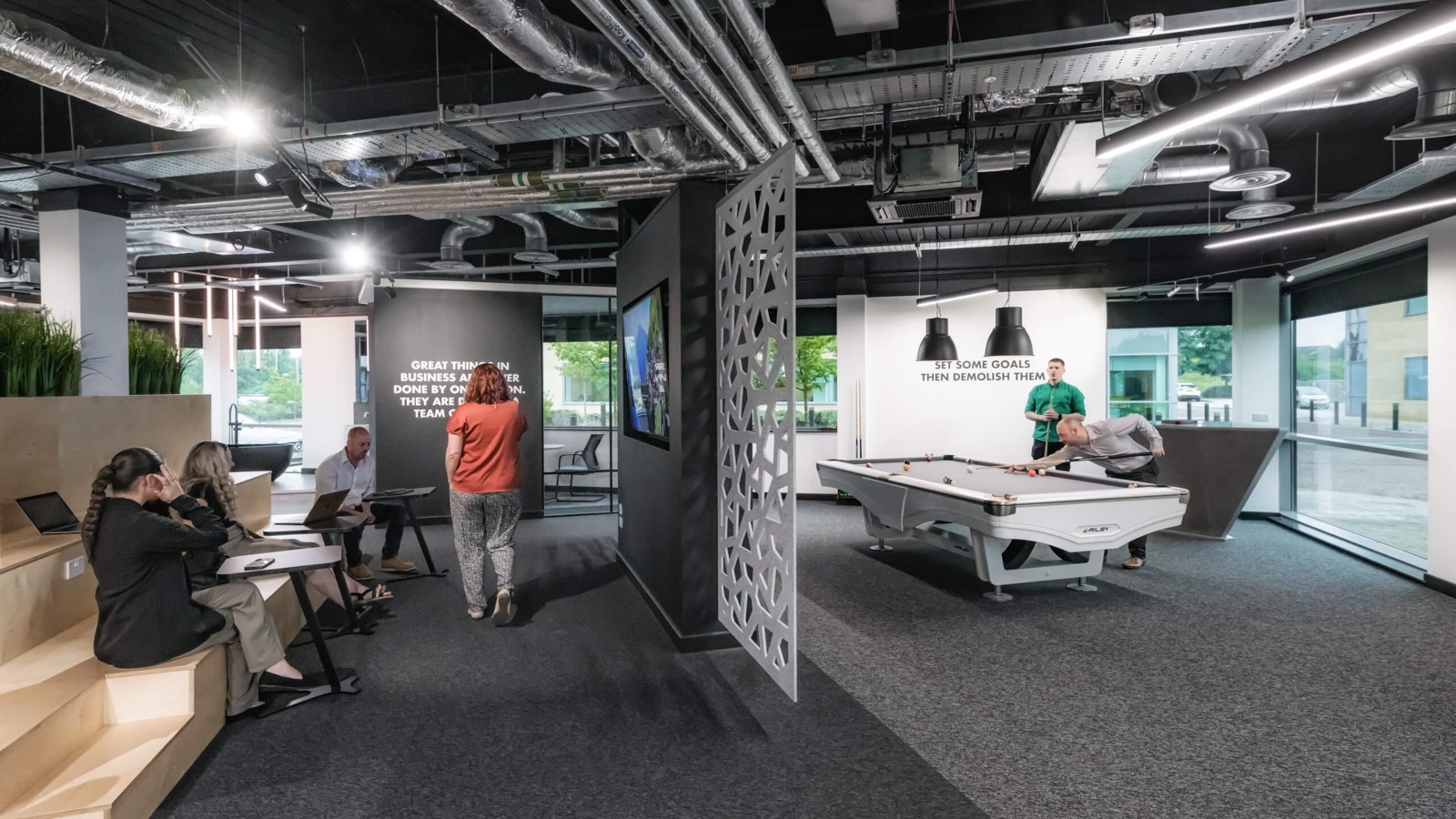 Breakout and games area at Lusso, colleagues meeting on banquette seating beside a pool table and wall-mounted screens
