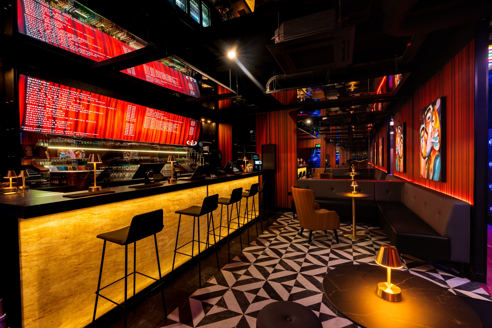 Pipeworks bar with an under-lit gold counter, red LED drinks boards and a geometric tiled floor