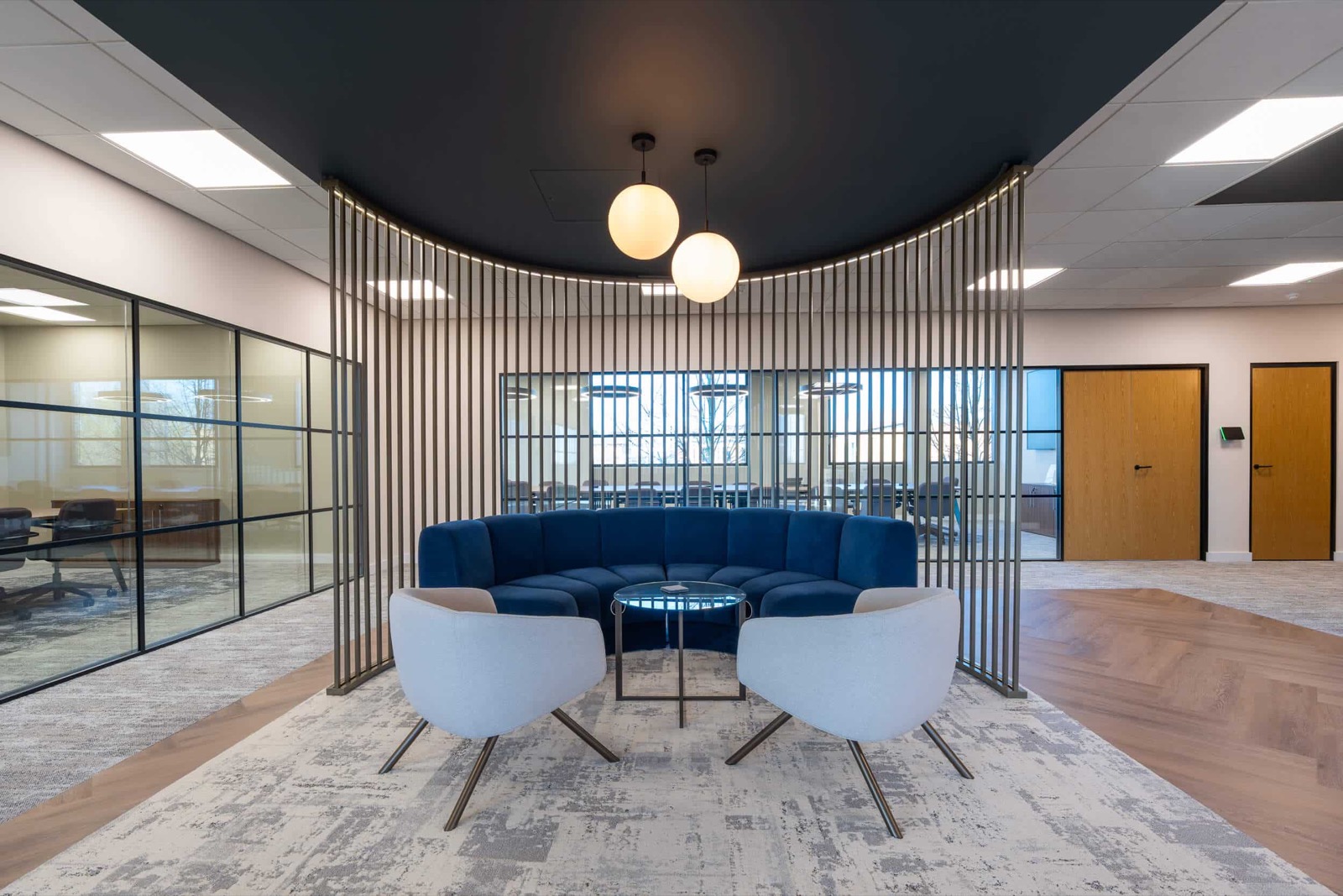 Curved blue banquette and armchairs at Renew Holdings, in front of a fluted screen beneath a circular dark ceiling feature