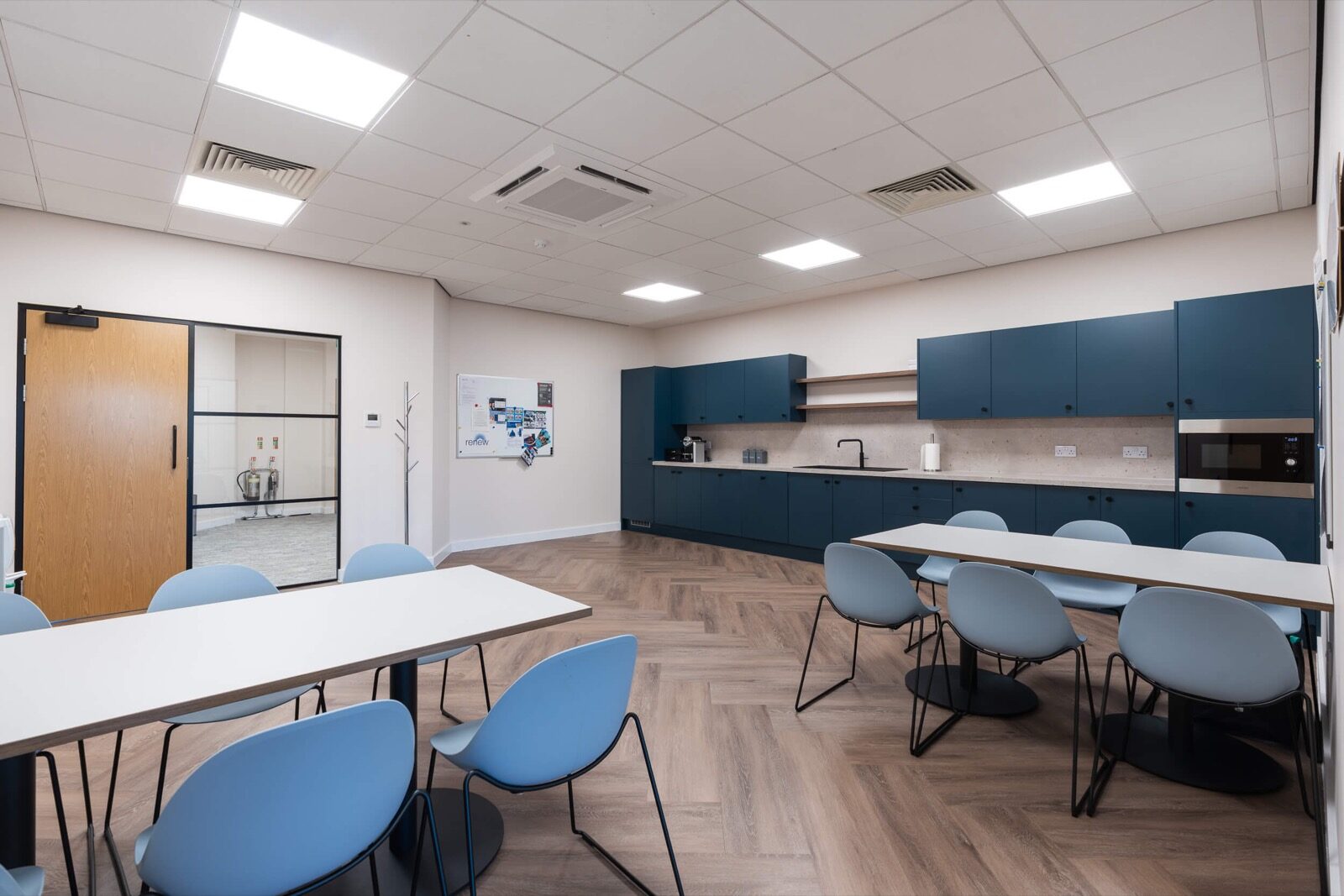 Tea point at Renew Holdings, with navy units, a run of worktop and a dining table with blue chairs alongside