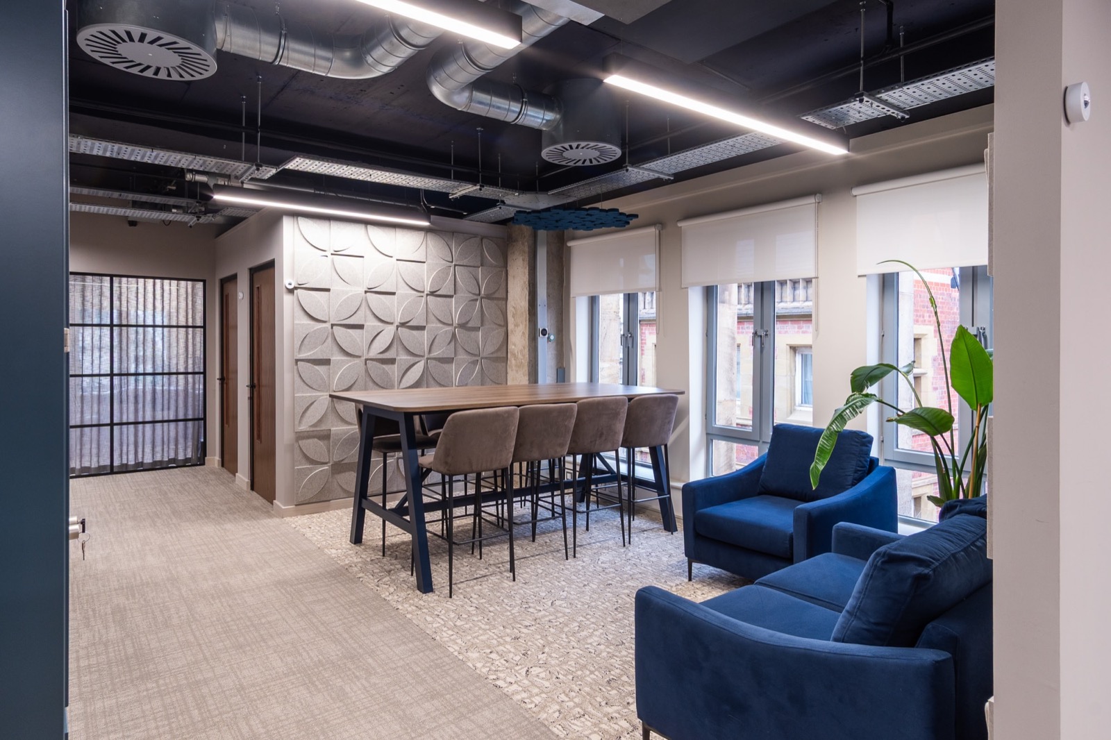 Refurbished floor at Spire Barristers, with navy soft seating, exposed services and arched windows
