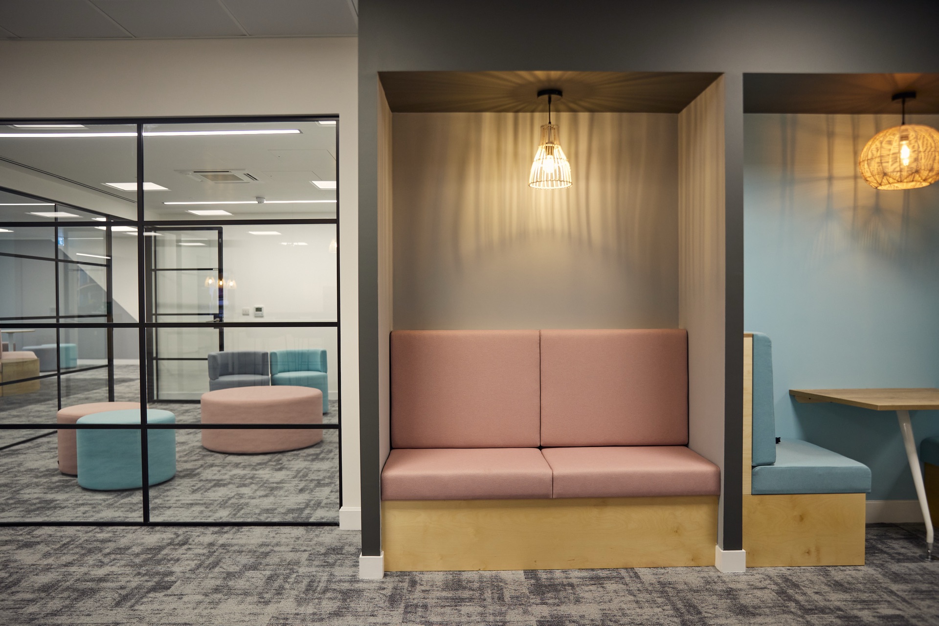 University booth seating with pastel pink and blue upholstery and pendant lighting