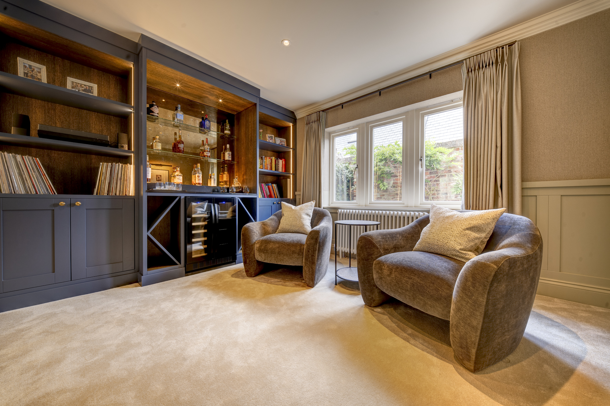 Bespoke home bar and library snug with backlit shelving and an integrated wine fridge
