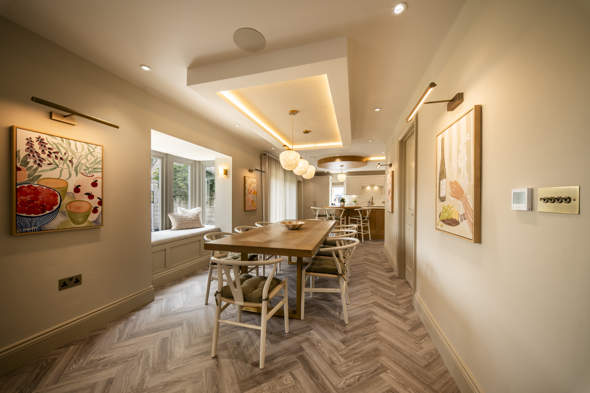 Open-plan dining area and hallway with a bay window seat and gallery wall, opening through to the kitchen
