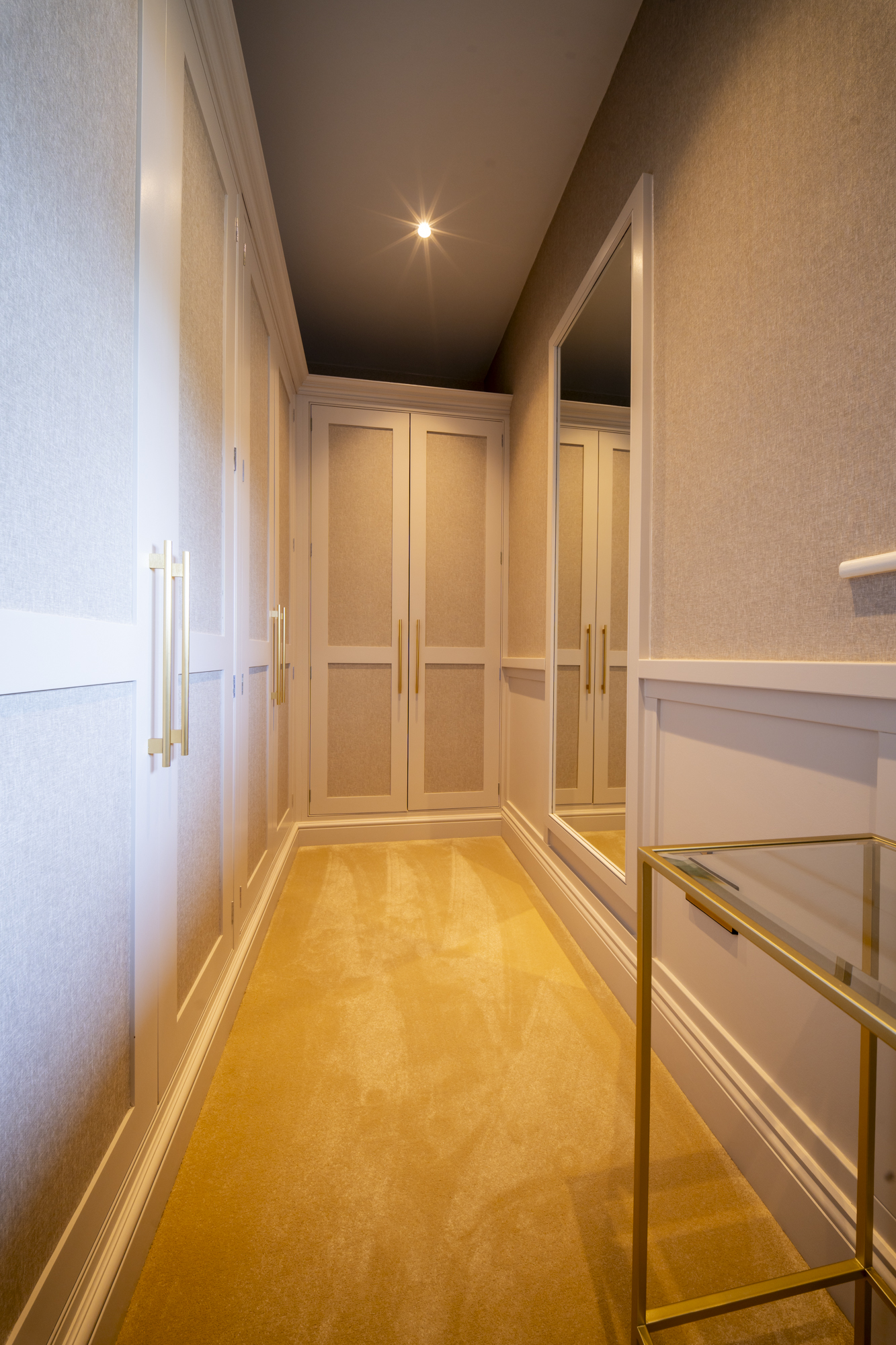 Bespoke fitted dressing room joinery at Well House with a glass and brass console table