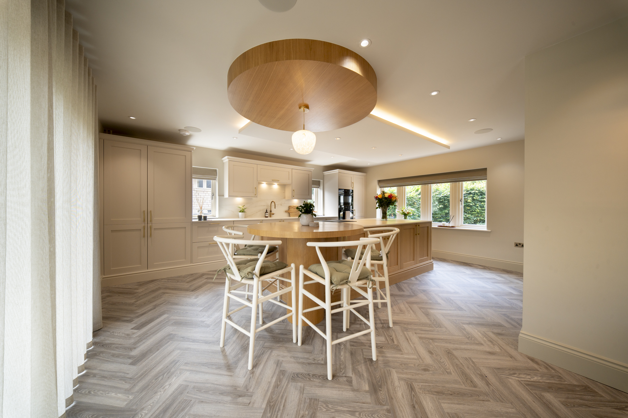Open-plan kitchen extension with a round oak table, herringbone floor and statement pendant light