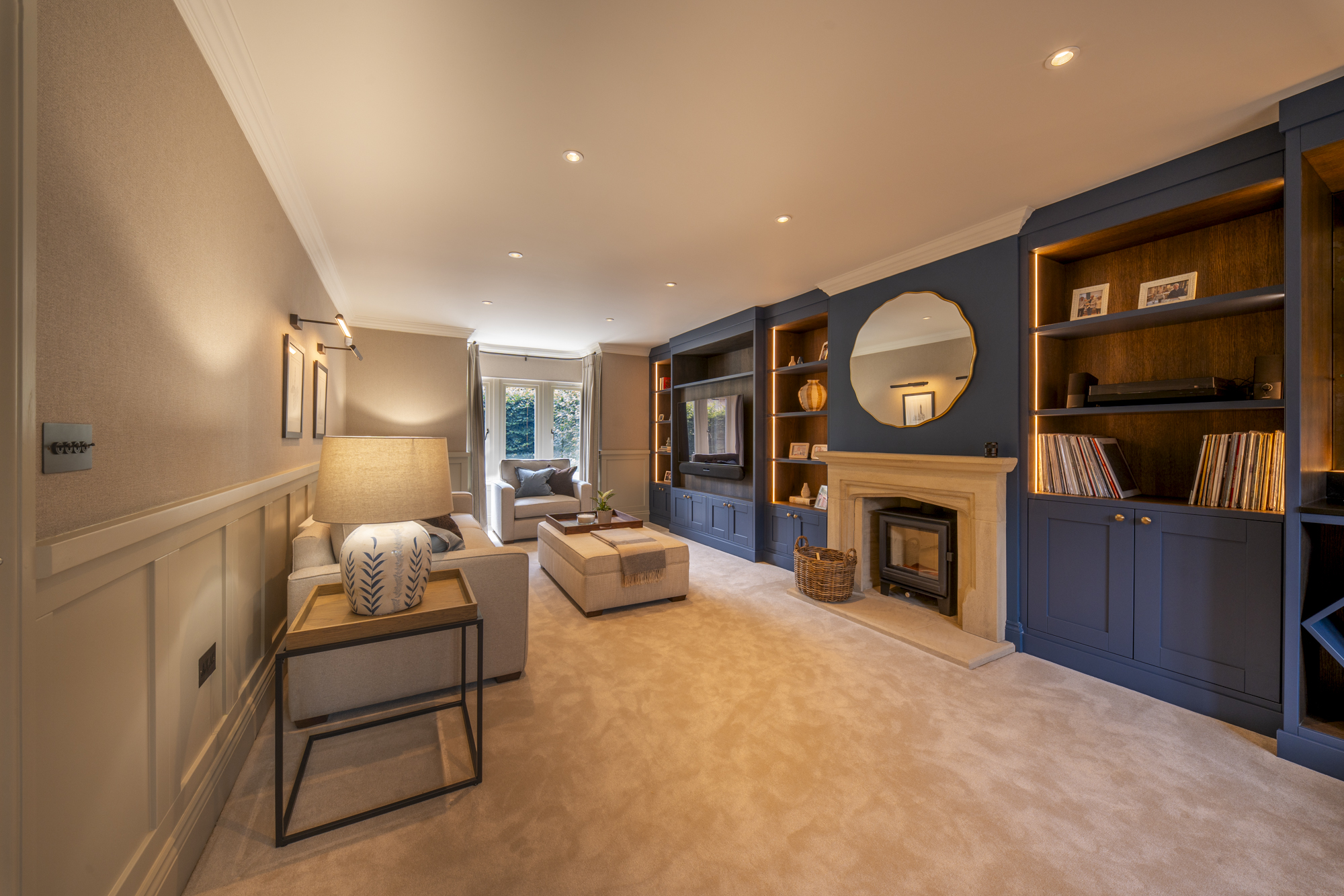 Living room at Well House, with bespoke navy joinery, open shelving and a fireplace