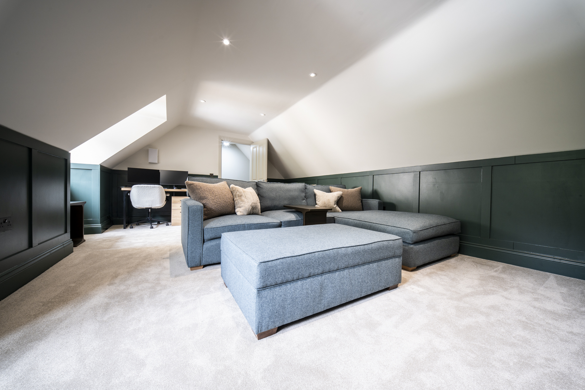 Loft media room and home office with fitted panelling beneath the roofline