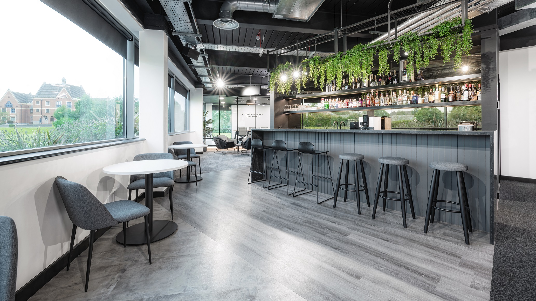 Bar at Lusso with a slatted grey counter, bar stools and trailing planting above the bottle shelving